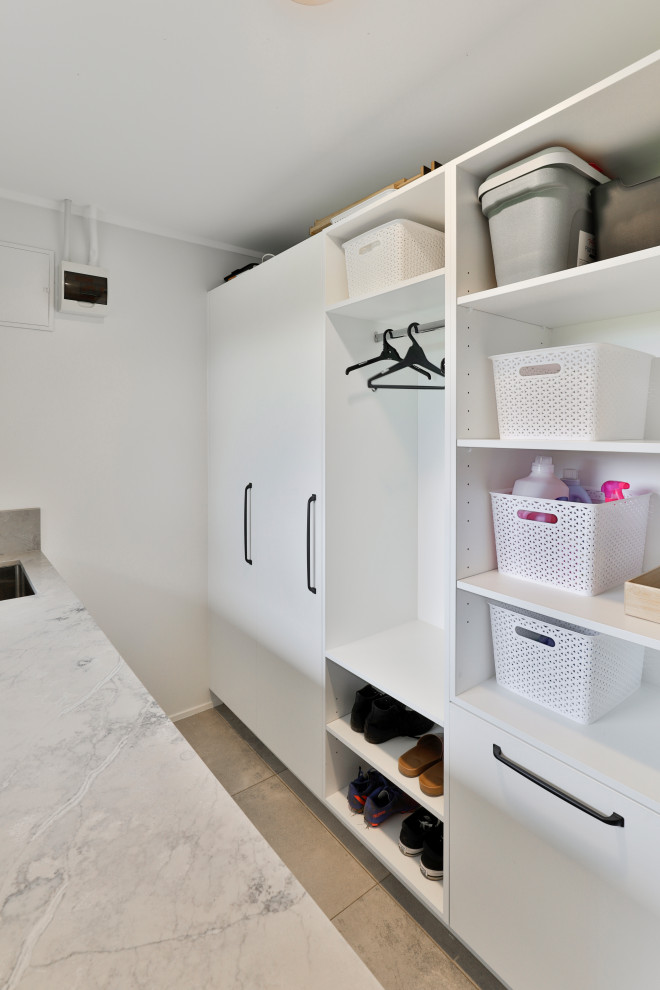 Medium sized modern utility room in Auckland with a submerged sink, white cabinets and a side by side washer and dryer.
