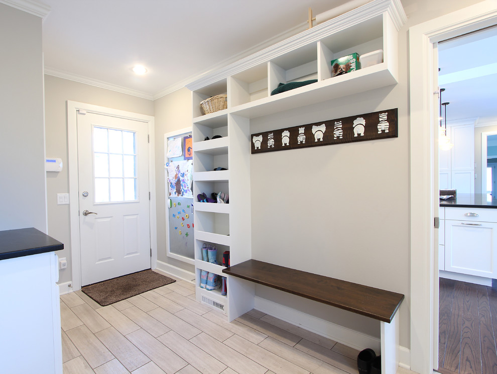Photo of a mid-sized transitional mudroom in Other with grey walls, limestone floors, a single front door, a white front door and beige floor.
