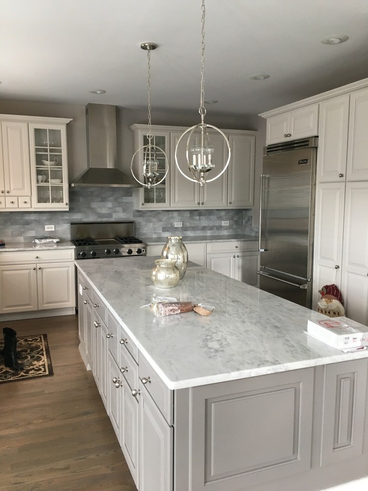 Inspiration for a mid-sized modern u-shaped eat-in kitchen in Chicago with raised-panel cabinets, white cabinets, quartz benchtops, grey splashback, subway tile splashback, stainless steel appliances, light hardwood floors, with island and brown floor.