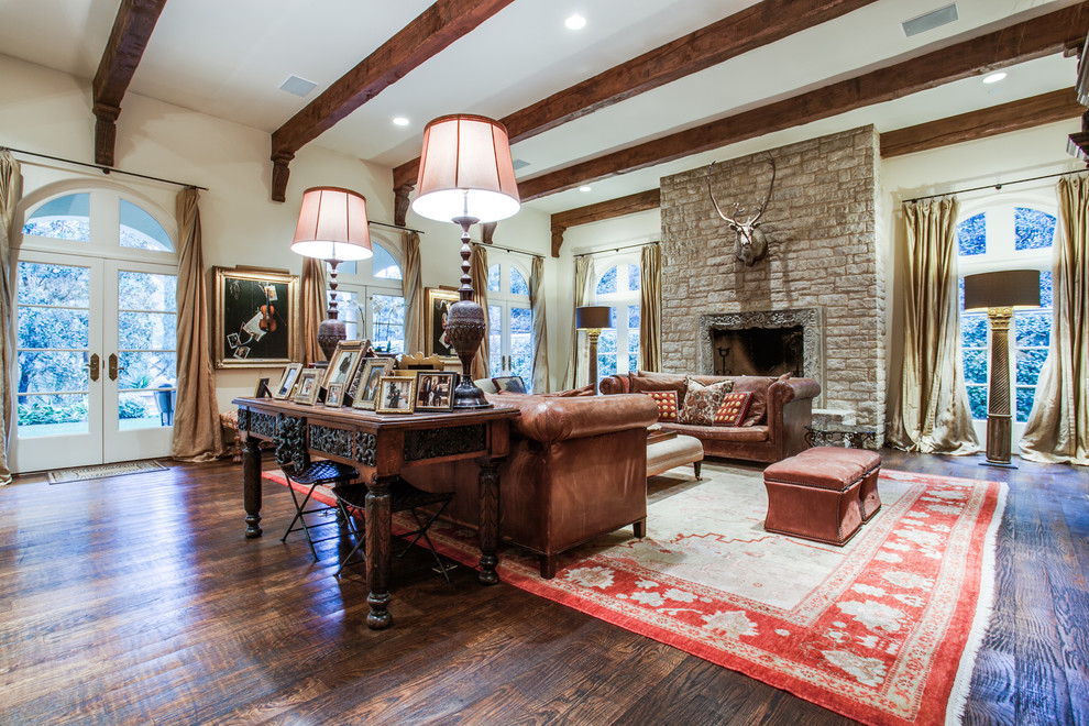 Photo of an expansive mediterranean formal enclosed living room in Dallas with white walls, dark hardwood floors, a standard fireplace, a stone fireplace surround and no tv.