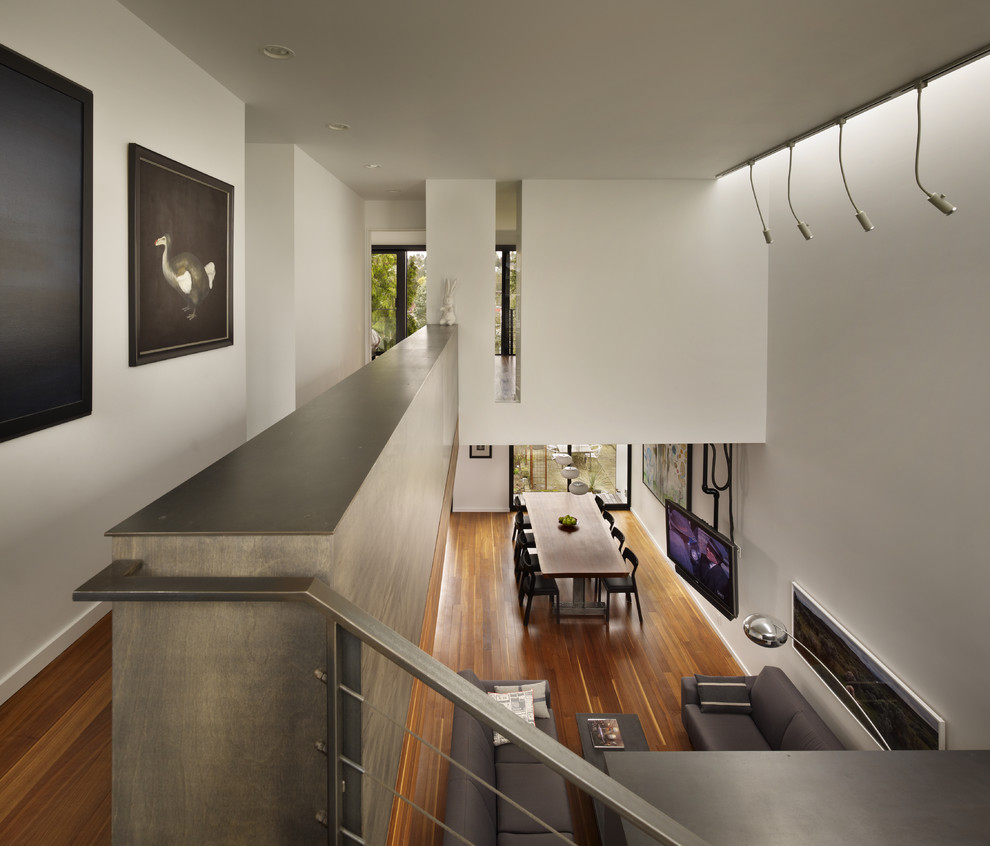 This is an example of a small modern hallway in Seattle with white walls and medium hardwood floors.