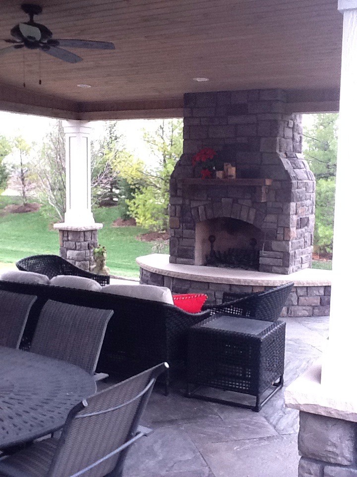 Mid-sized traditional backyard patio in Indianapolis with a fire feature, concrete pavers and a roof extension.