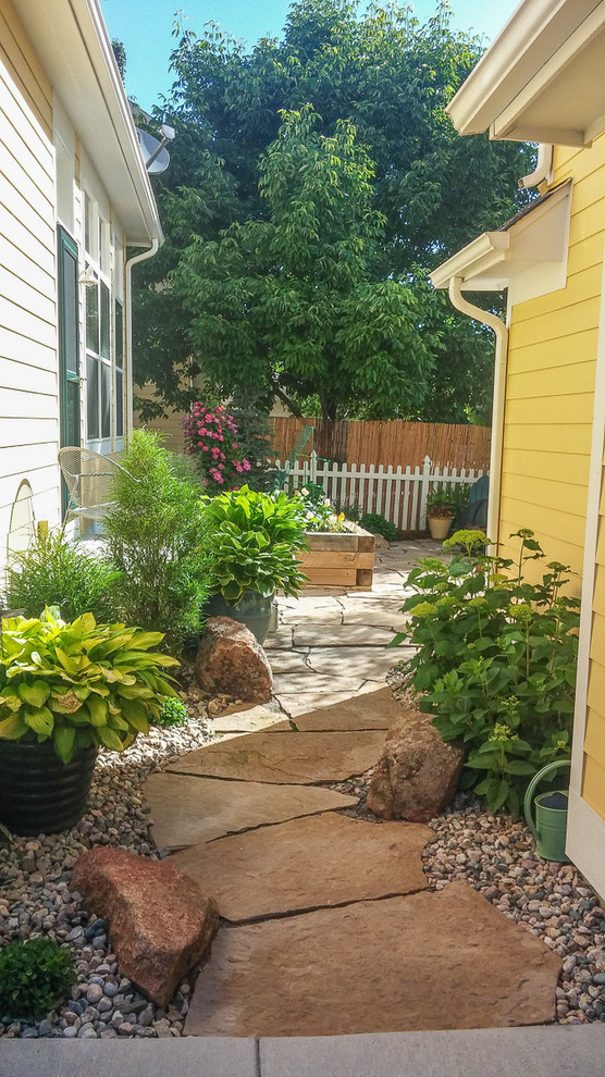 Inspiration for a mid-sized traditional backyard partial sun garden for spring in Denver with natural stone pavers.