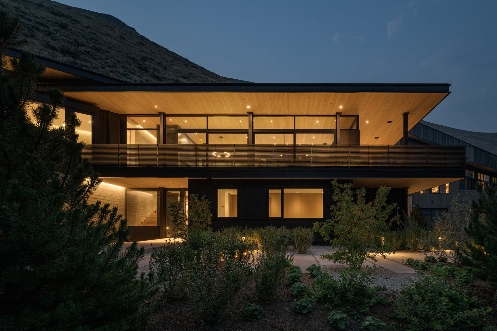 Cette photo montre une grande façade de maison noire moderne en bois à un étage avec un toit plat.