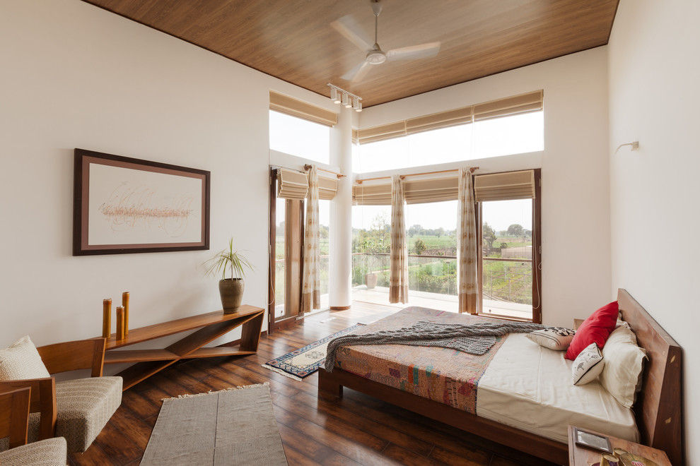 Inspiration for a contemporary master bedroom in Delhi with white walls, dark hardwood floors and brown floor.