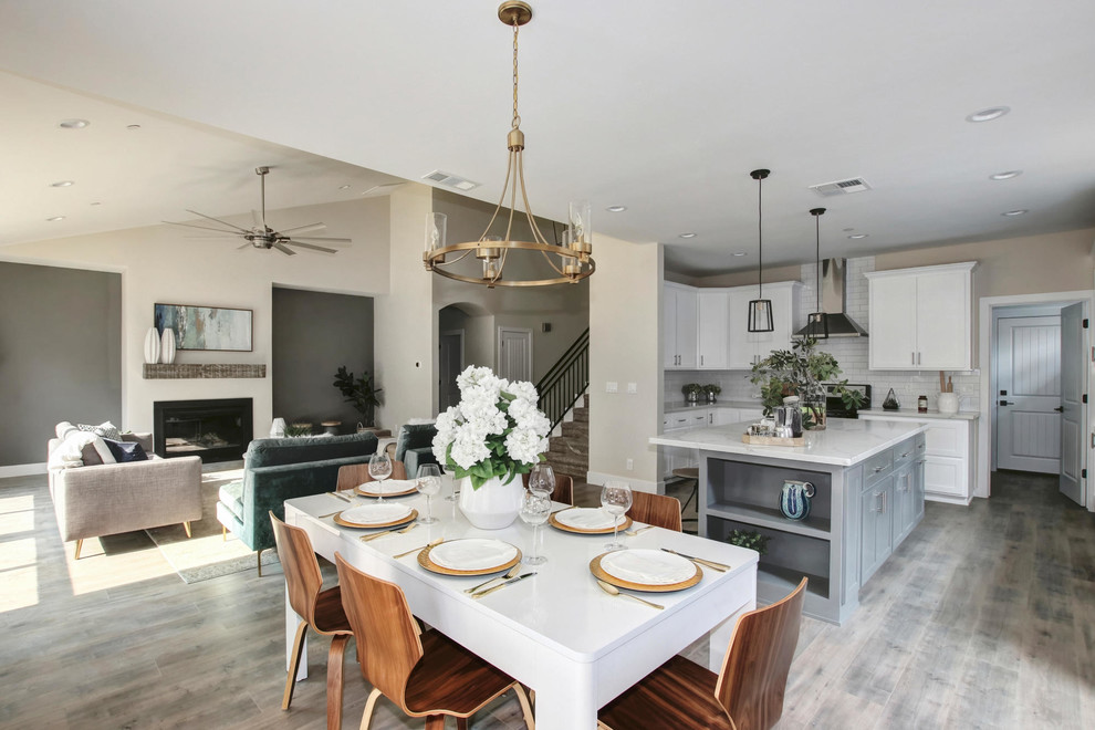 Mid-sized traditional u-shaped open plan kitchen in Sacramento with a farmhouse sink, shaker cabinets, white cabinets, quartzite benchtops, white splashback, subway tile splashback, stainless steel appliances, laminate floors, with island, grey floor and white benchtop.