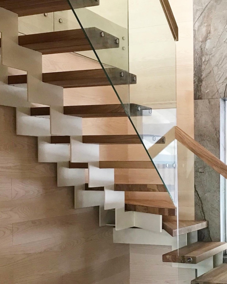 Diseño de escalera en L sin contrahuella con escalones de madera, barandilla de vidrio y machihembrado