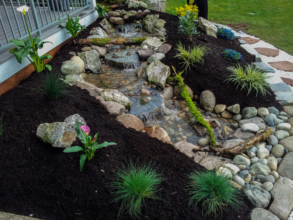 Photo of a mid-sized rustic full sun backyard stone water fountain landscape in Seattle for spring.