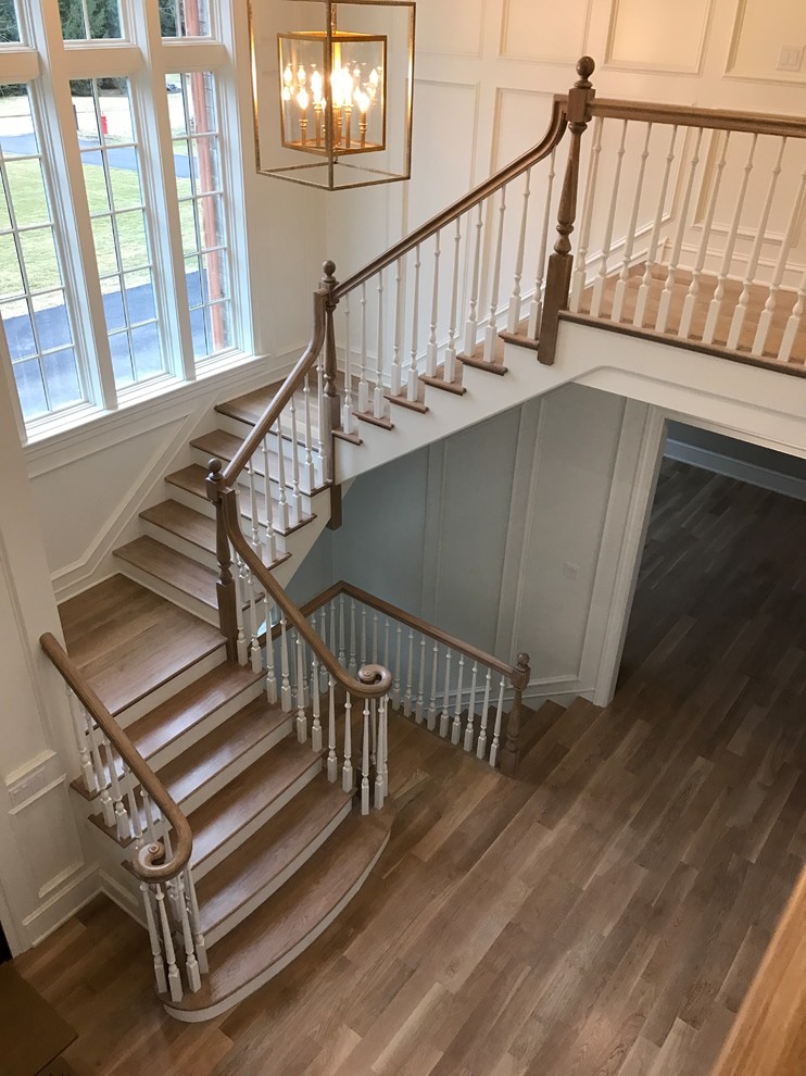 This is an example of a large traditional wood u-shaped staircase in Chicago with painted wood risers and wood railing.