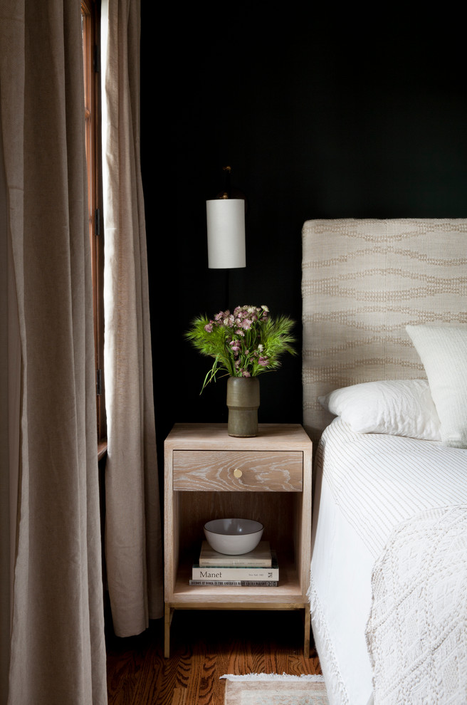This is an example of a transitional bedroom in Los Angeles with black walls and medium hardwood floors.