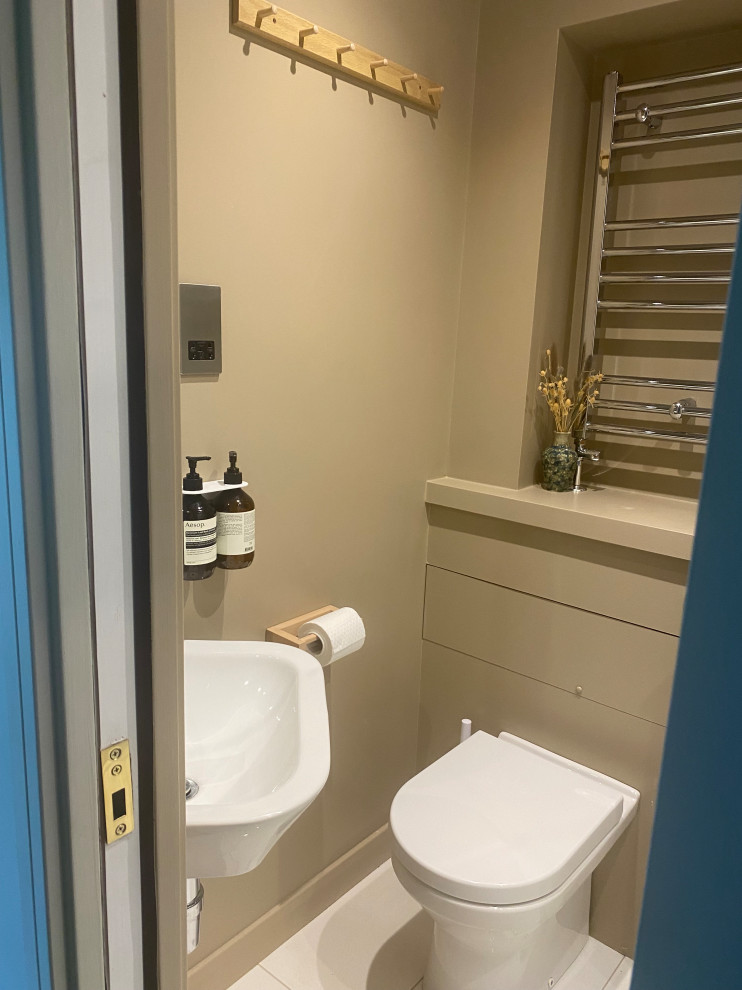Immagine di un piccolo bagno di servizio costiero con WC sospeso, piastrelle bianche, piastrelle a specchio, pareti beige, pavimento in gres porcellanato, lavabo sospeso, pavimento bianco e mobile bagno sospeso