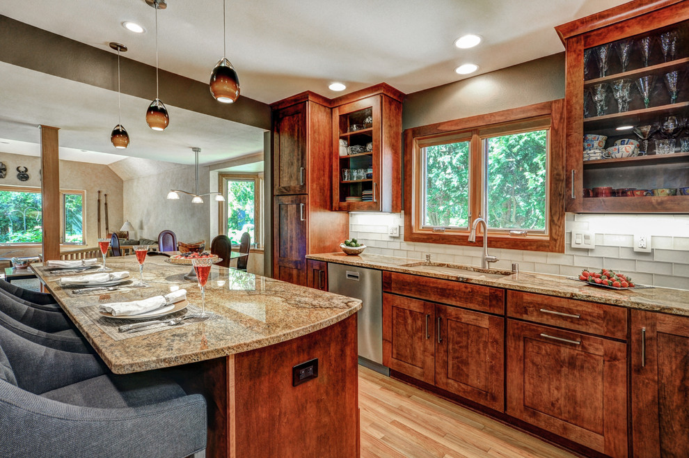 Inspiration for a large transitional l-shaped light wood floor enclosed kitchen remodel in Milwaukee with an undermount sink, shaker cabinets, medium tone wood cabinets, granite countertops, beige backsplash, glass tile backsplash, stainless steel appliances and an island