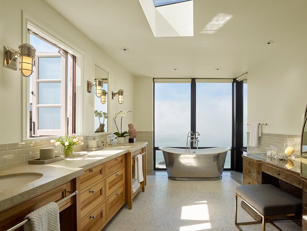 This is an example of a mediterranean bathroom in San Francisco with recessed-panel cabinets, brown cabinets, a freestanding tub, beige tile, subway tile and an undermount sink.