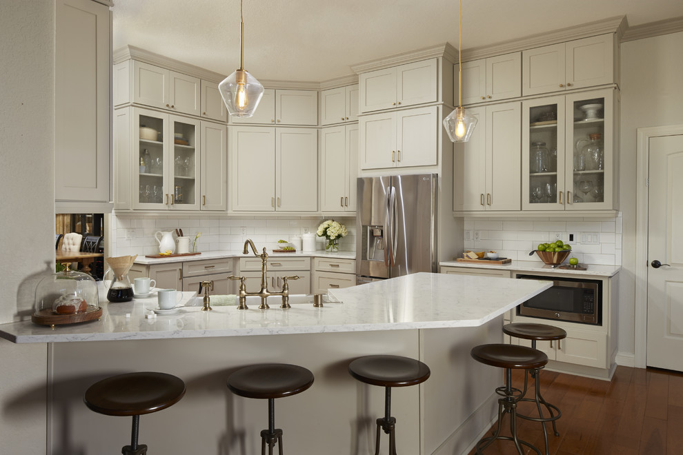 Example of a mid-sized transitional u-shaped medium tone wood floor and brown floor enclosed kitchen design in Atlanta with a farmhouse sink, shaker cabinets, gray cabinets, quartz countertops, white backsplash, subway tile backsplash, stainless steel appliances, a peninsula and white countertops