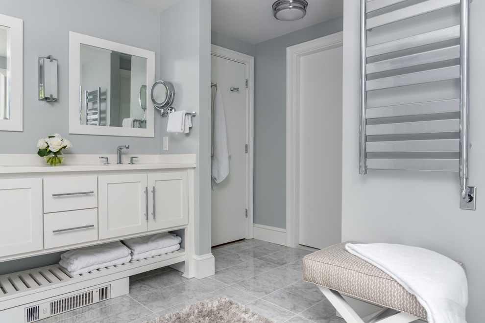This is an example of a mid-sized transitional master bathroom in Boston with furniture-like cabinets, white cabinets, an alcove shower, grey walls, marble floors, an undermount sink, solid surface benchtops, grey floor, a hinged shower door and white benchtops.
