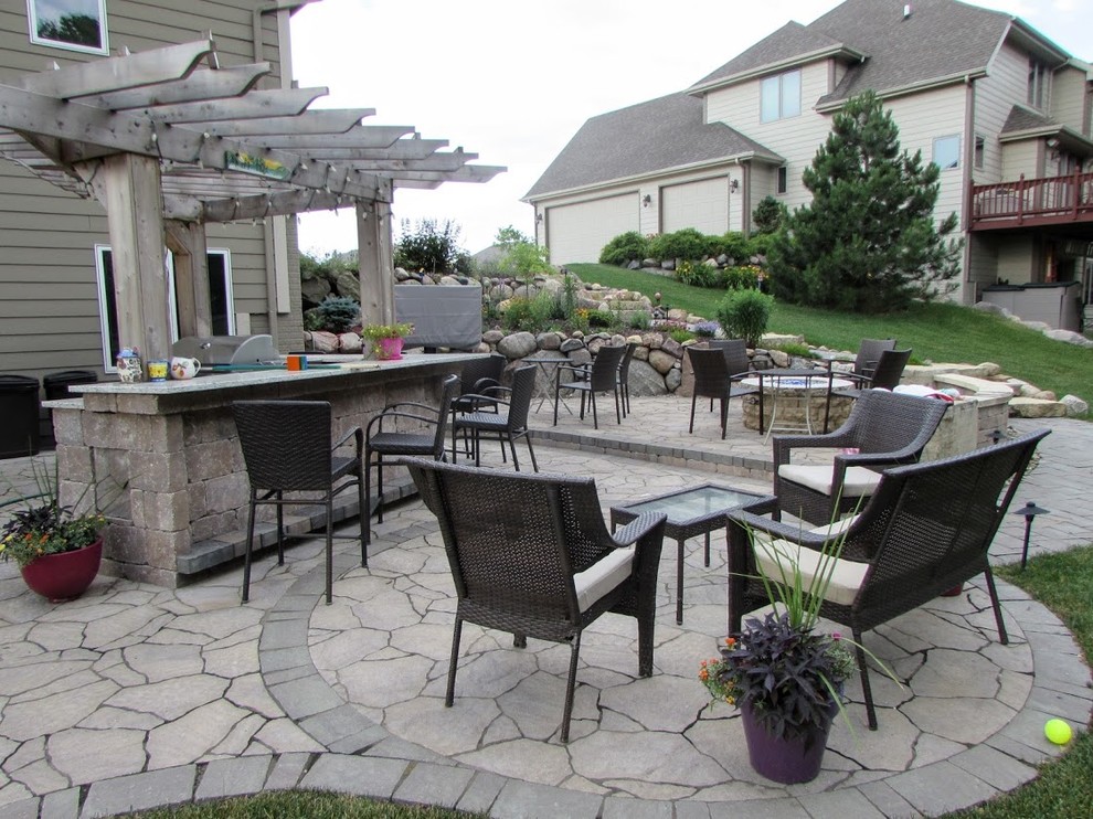 This is an example of a large traditional backyard patio in Other with a fire feature, natural stone pavers and no cover.