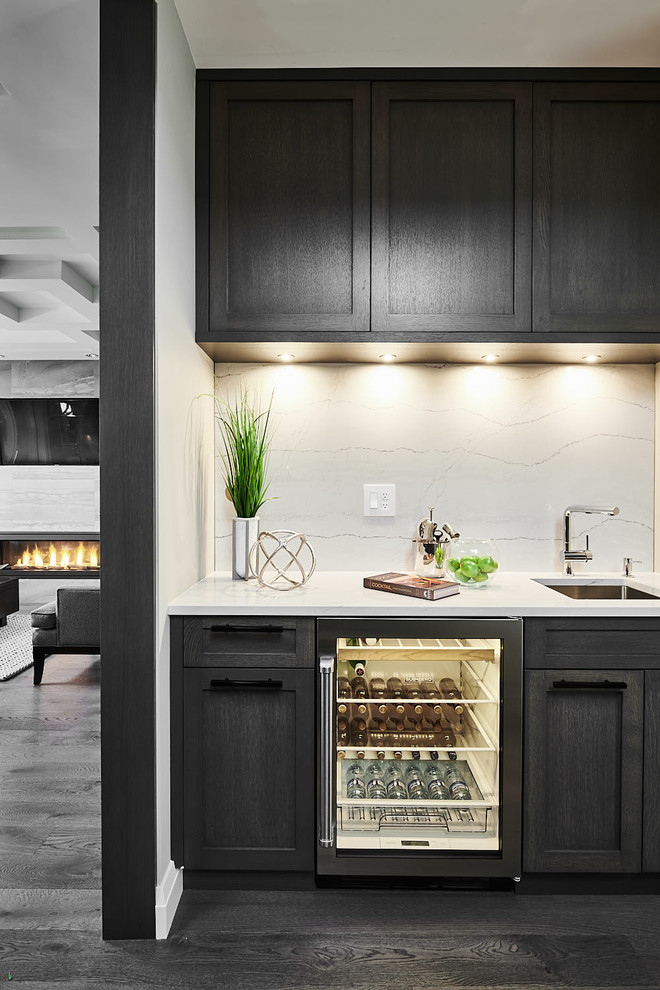 Design ideas for a small contemporary single-wall wet bar in Vancouver with an undermount sink, shaker cabinets, dark wood cabinets, marble benchtops, white splashback, porcelain splashback, dark hardwood floors and brown floor.
