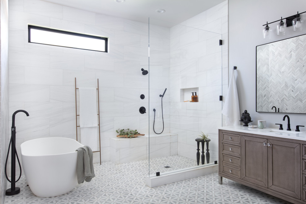 Inspiration for an expansive transitional master bathroom in San Diego with shaker cabinets, brown cabinets, a freestanding tub, an open shower, white tile, porcelain tile, grey walls, marble floors, an undermount sink, engineered quartz benchtops, white floor, an open shower, white benchtops, a shower seat, a single vanity and a freestanding vanity.