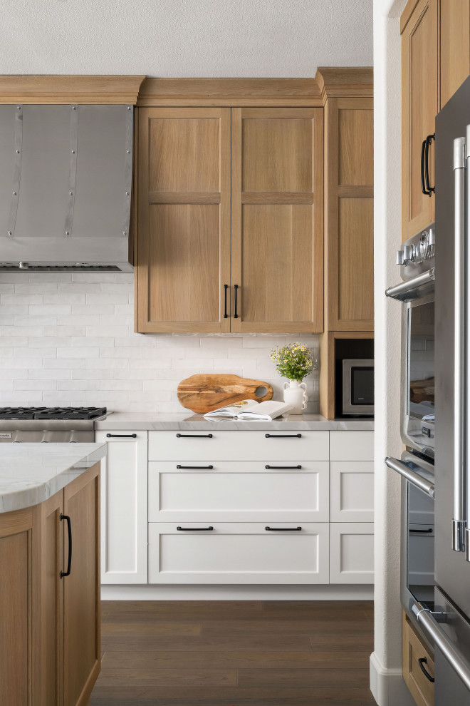 Inspiration for a mid-sized transitional l-shaped eat-in kitchen in San Diego with an undermount sink, shaker cabinets, light wood cabinets, quartzite benchtops, white splashback, ceramic splashback, stainless steel appliances, vinyl floors, with island, brown floor and grey benchtop.