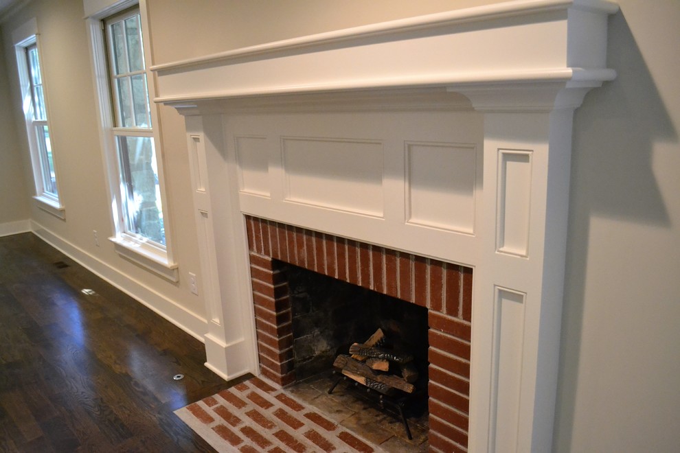 Photo of a mid-sized country open concept family room in Kansas City with dark hardwood floors, brown floor, white walls, a standard fireplace and a brick fireplace surround.