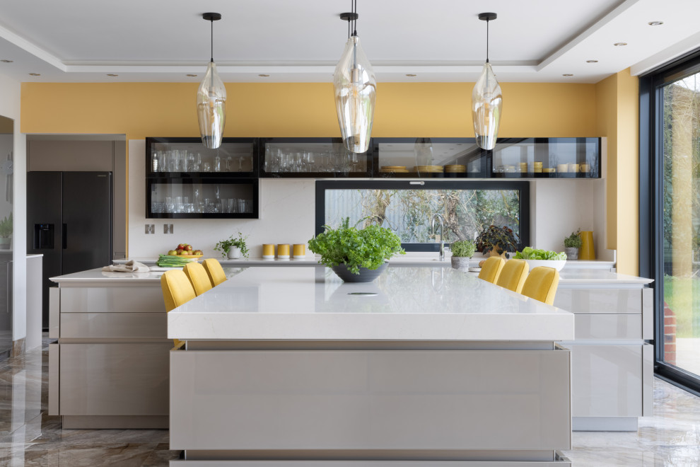 Inspiration for a large contemporary open plan kitchen in Hampshire with an integrated sink, glass-front cabinets, beige cabinets, quartz benchtops, black appliances, porcelain floors, with island, beige floor and beige benchtop.