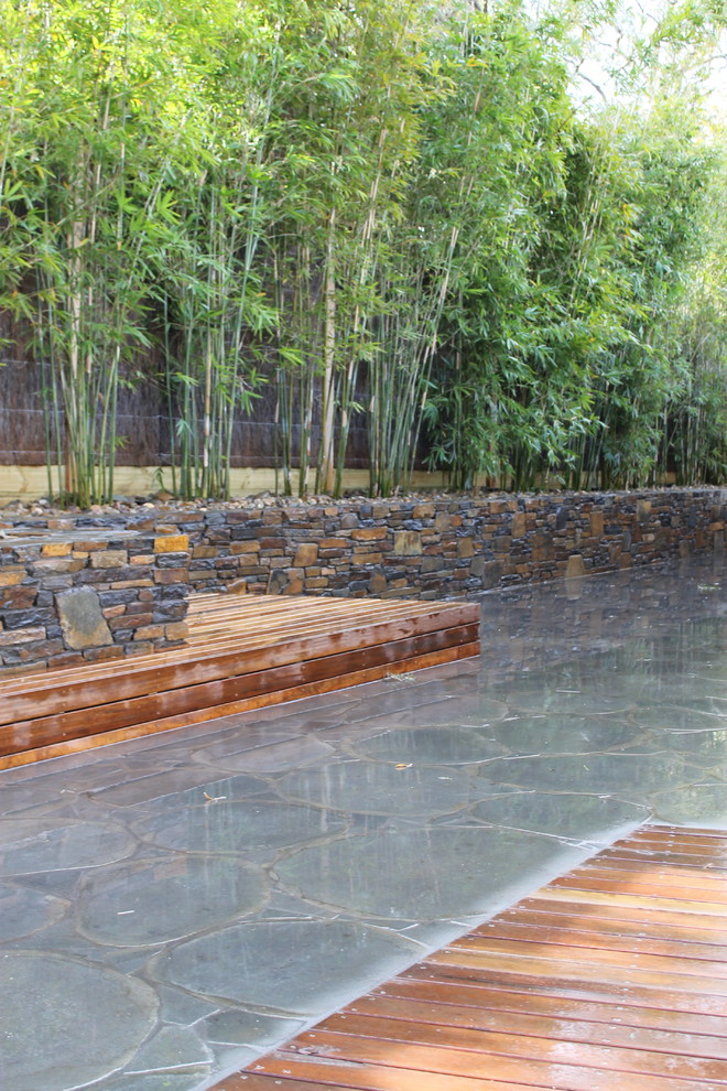 This is an example of a mid-sized traditional backyard shaded garden in Melbourne with a retaining wall and natural stone pavers.