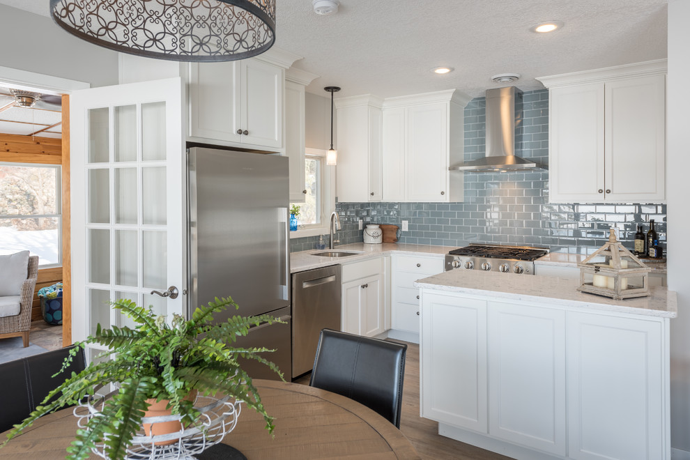 Inspiration for a small transitional u-shaped eat-in kitchen in Minneapolis with shaker cabinets, white cabinets, a peninsula, an undermount sink, quartzite benchtops, grey splashback, subway tile splashback, stainless steel appliances, light hardwood floors, beige floor and white benchtop.