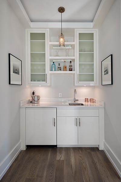 This is an example of a transitional single-wall wet bar in New York with flat-panel cabinets, white cabinets, quartzite benchtops, medium hardwood floors and beige floor.
