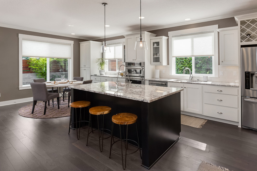 Inspiration for a transitional single-wall eat-in kitchen in DC Metro with an undermount sink, shaker cabinets, white cabinets, white splashback, subway tile splashback, stainless steel appliances, dark hardwood floors, with island, brown floor and grey benchtop.