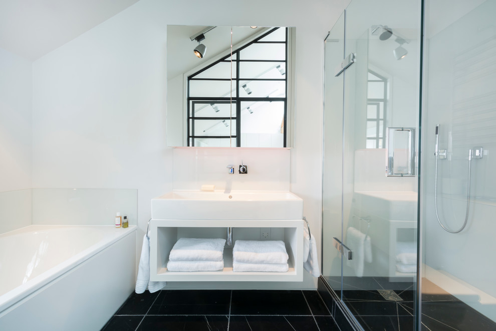 Inspiration for a large industrial master bathroom in London with a wall-mount sink, white cabinets, solid surface benchtops, a corner tub, a curbless shower, white walls and marble floors.