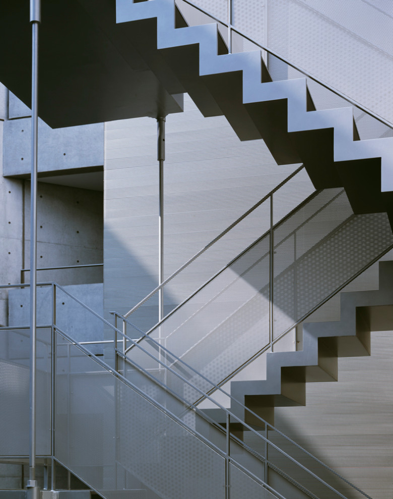 На фото: металлическая лестница на больцах, среднего размера в стиле модернизм с металлическими ступенями, металлическими перилами и панелями на части стены