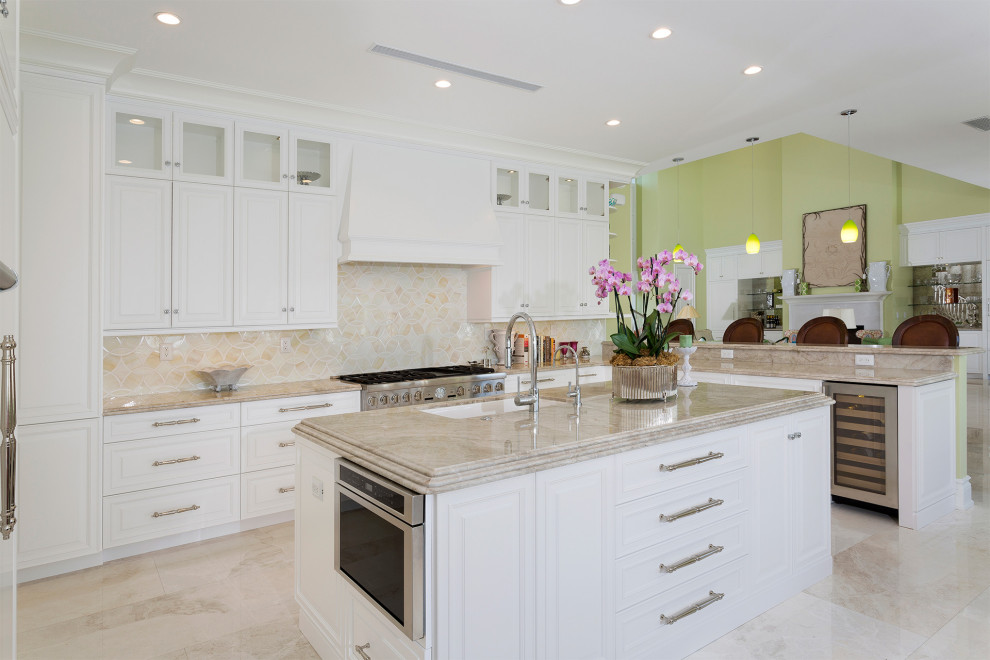 This is an example of a large transitional l-shaped open plan kitchen in Miami with an undermount sink, raised-panel cabinets, white cabinets, marble benchtops, beige splashback, mosaic tile splashback, stainless steel appliances, porcelain floors, with island, beige floor and beige benchtop.