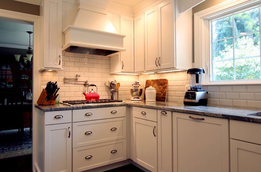 Inspiration for a mid-sized transitional u-shaped eat-in kitchen in Detroit with an undermount sink, shaker cabinets, white cabinets, granite benchtops, white splashback, ceramic splashback, stainless steel appliances, medium hardwood floors and no island.