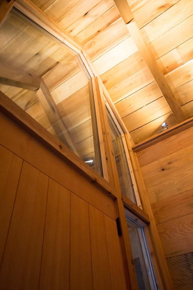 Large mountain style ceramic tile foyer photo with brown walls and a medium wood front door