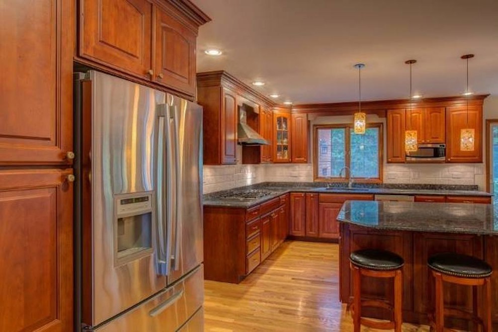 This is an example of a mid-sized traditional l-shaped kitchen in Birmingham with beaded inset cabinets, medium wood cabinets, granite benchtops, stainless steel appliances and light hardwood floors.