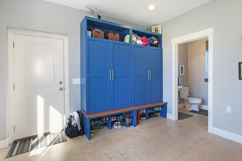 Photo of a large country utility room in Grand Rapids with shaker cabinets, blue cabinets, grey walls, concrete floors and grey floor.