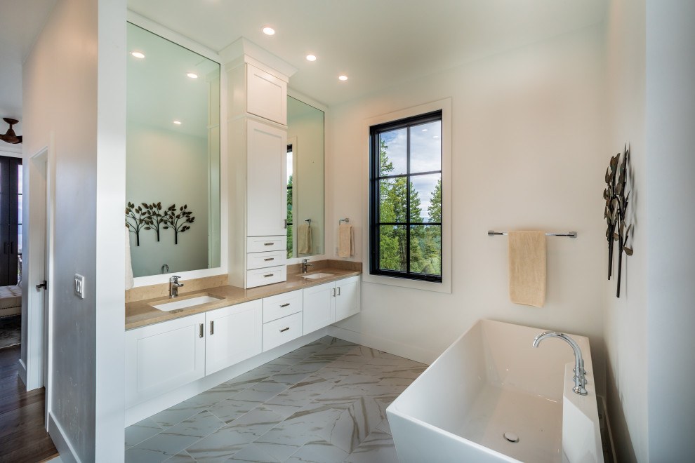 Freestanding bathtub - large transitional gray floor freestanding bathtub idea with white cabinets, white walls, quartzite countertops, a hinged shower door, brown countertops, shaker cabinets and an undermount sink