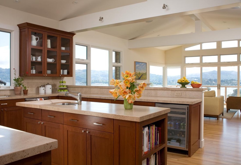 Large contemporary u-shaped eat-in kitchen in San Francisco with flat-panel cabinets, an undermount sink, dark wood cabinets, limestone benchtops, beige splashback, stainless steel appliances, light hardwood floors, with island, stone slab splashback and beige benchtop.
