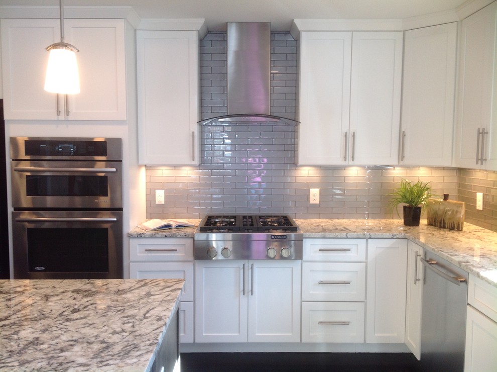 Example of a mid-sized transitional galley dark wood floor eat-in kitchen design in Denver with a double-bowl sink, recessed-panel cabinets, white cabinets, granite countertops, gray backsplash, ceramic backsplash, stainless steel appliances and an island