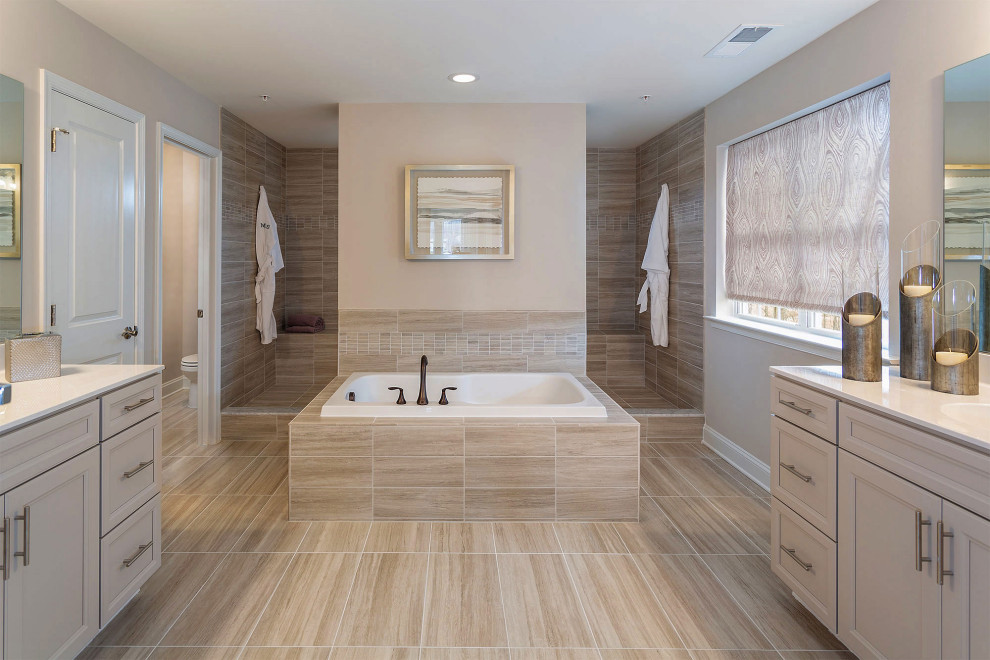 This is an example of a transitional master bathroom in Baltimore with recessed-panel cabinets, beige cabinets, a drop-in tub, an alcove shower, brown tile, beige walls, wood-look tile, an integrated sink, brown floor, an open shower, white benchtops, a shower seat, an enclosed toilet, a double vanity and a built-in vanity.