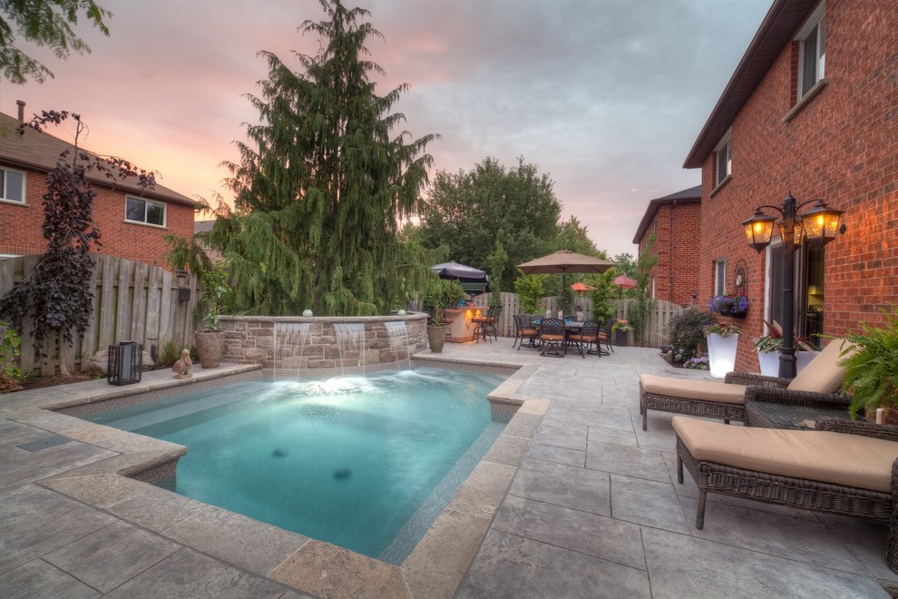 Small contemporary backyard custom-shaped pool in Toronto with a water feature and stamped concrete.