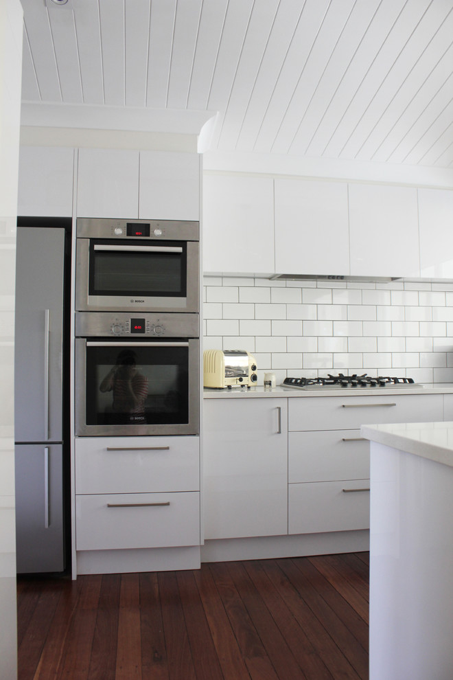 Inspiration for a contemporary kitchen in Brisbane with flat-panel cabinets, white cabinets, quartz benchtops, white splashback, subway tile splashback, stainless steel appliances and with island.