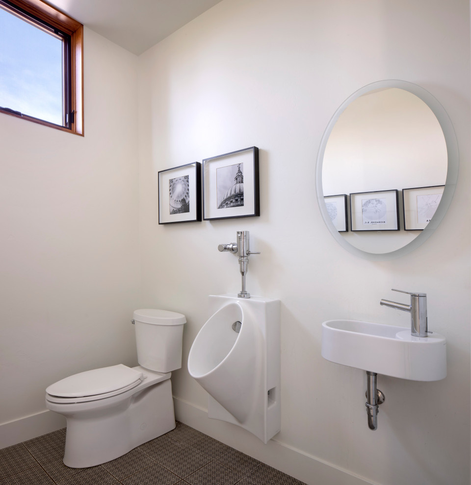Bild på ett rustikt toalett, med ett urinoar, vita väggar och ett väggmonterat handfat