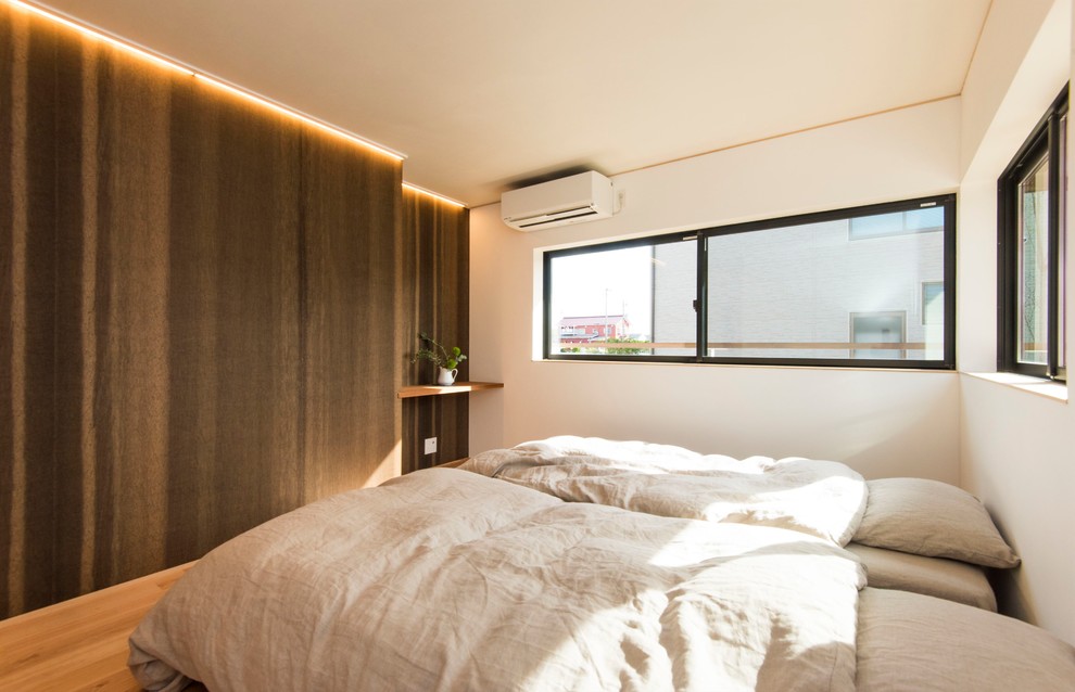 Modelo de dormitorio principal minimalista con paredes blancas, suelo de madera en tonos medios y suelo marrón