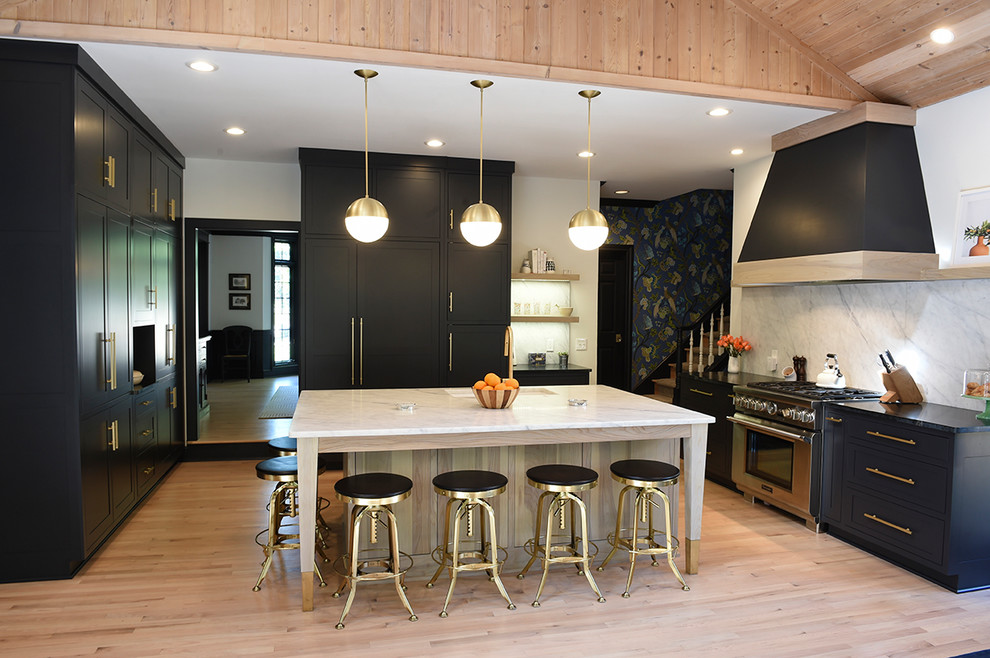 Example of a large trendy u-shaped light wood floor and beige floor kitchen design in Cleveland with an undermount sink, shaker cabinets, black cabinets, quartz countertops, white backsplash, stone slab backsplash, paneled appliances and an island