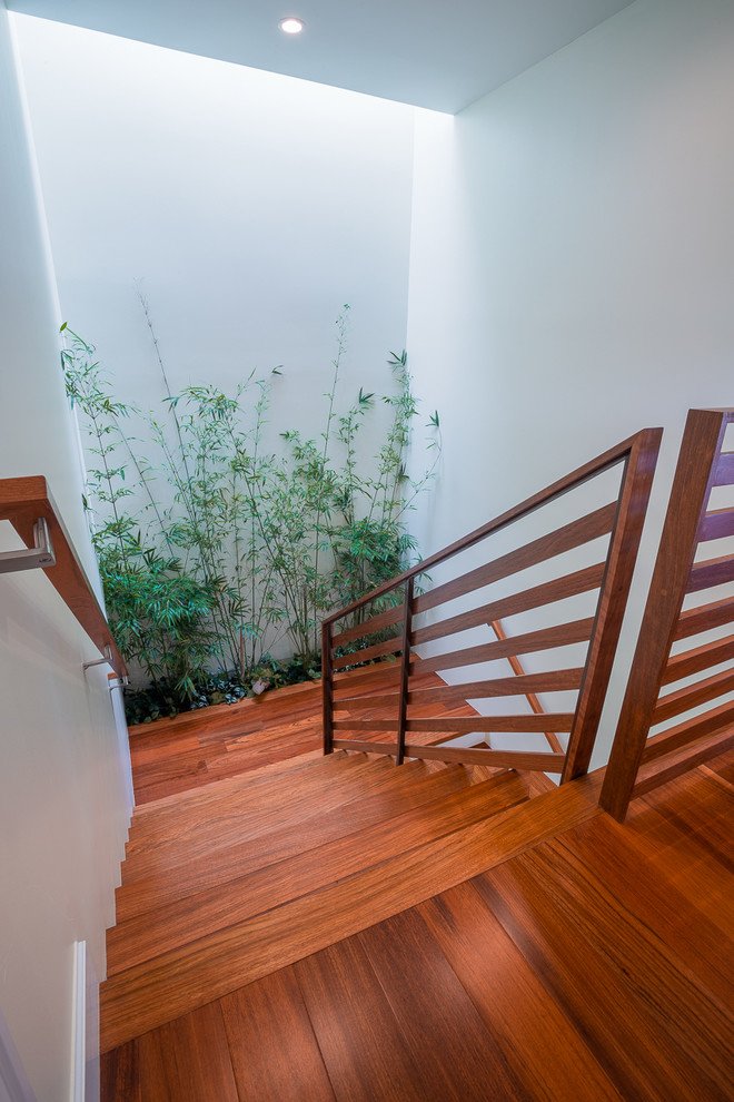 Design ideas for a mid-sized tropical wood u-shaped staircase in Hawaii with painted wood risers and wood railing.