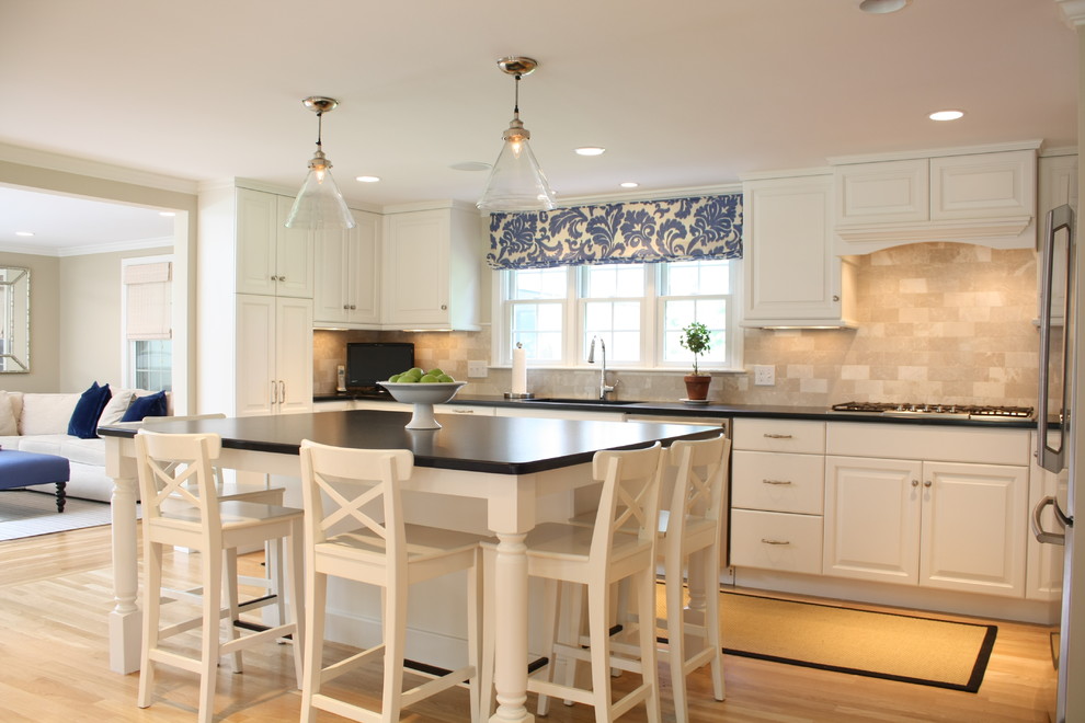 Design ideas for a mid-sized traditional u-shaped kitchen in Boston with an undermount sink, raised-panel cabinets, white cabinets, granite benchtops, beige splashback, stone tile splashback, stainless steel appliances, light hardwood floors and with island.