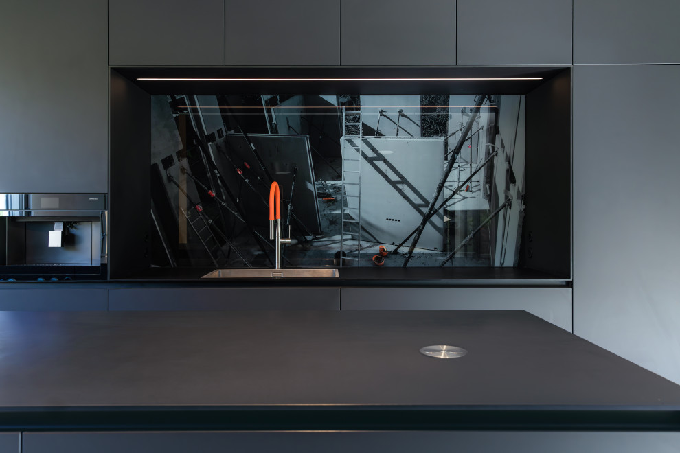 Inspiration for an expansive contemporary galley open plan kitchen in Frankfurt with flat-panel cabinets, black cabinets, laminate benchtops, glass sheet splashback, black appliances, with island and black benchtop.