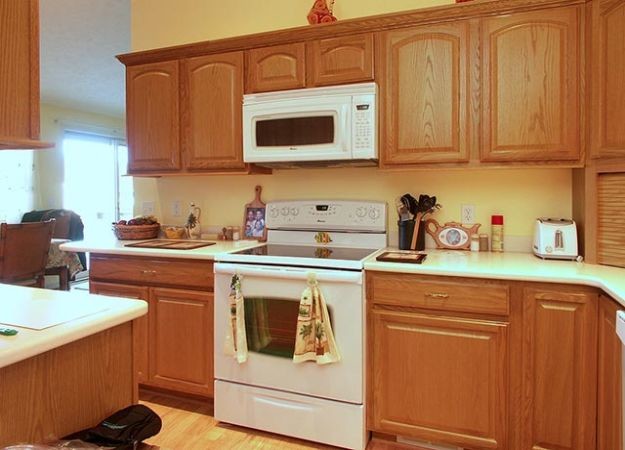 Example of a transitional u-shaped dark wood floor enclosed kitchen design with a double-bowl sink, medium tone wood cabinets, granite countertops, stainless steel appliances and an island