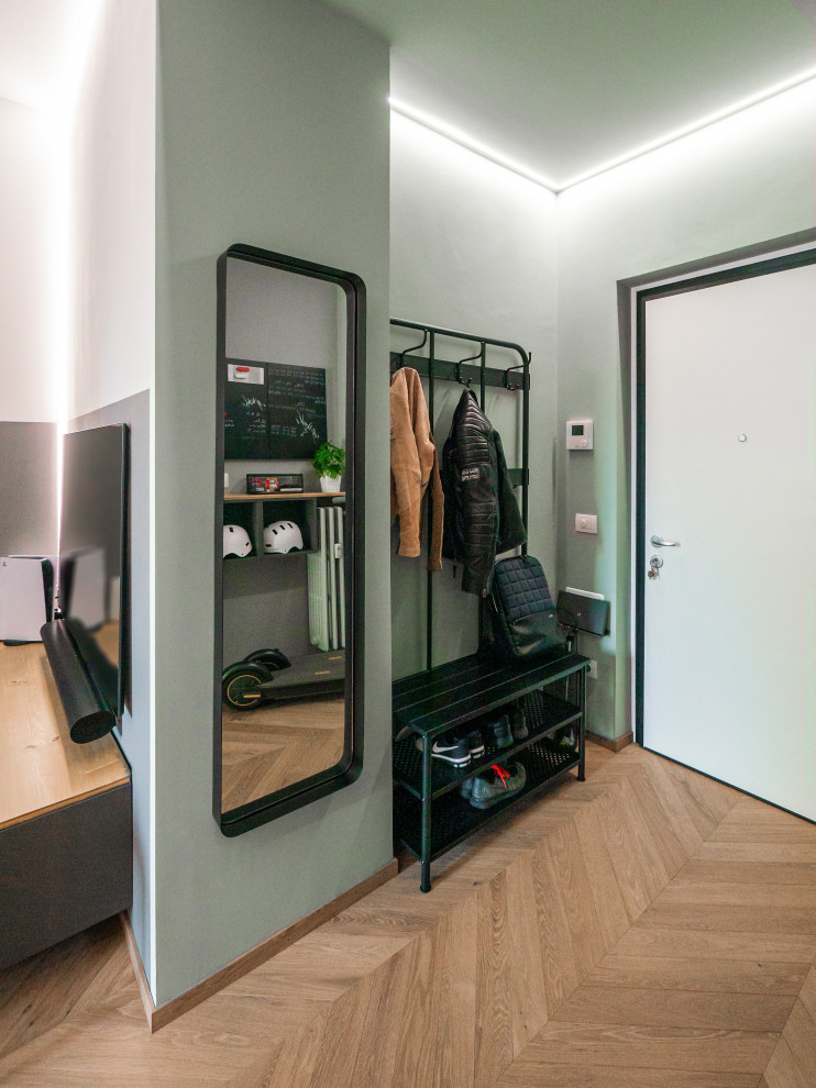 Example of a small urban light wood floor and tray ceiling entryway design in Milan with green walls and a white front door